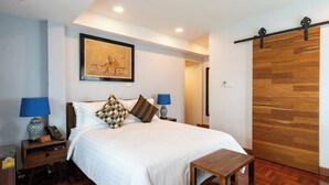 Habitación de hotel con cama, lámparas de noche, piso de madera, un cuadro en la pared y una puerta corredera.