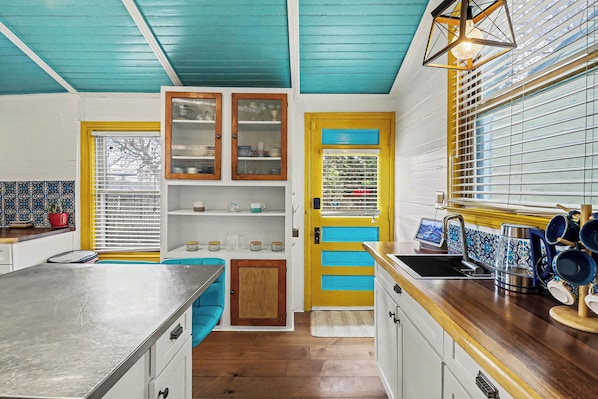 A kitchen with a wooden countertop, a sink, and a window with blinds.