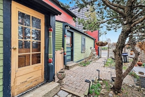 A row of colorful wooden houses with a paved walkway and a tree.