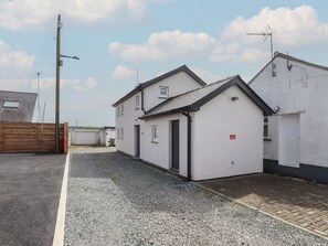 A residential area with two white houses, one with a garage, and a gravel driveway. - Kiloran (Rhosneigr)