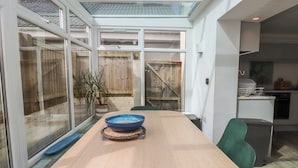 A modern kitchen with a dining area, large windows, and a view of the backyard. - Kiloran (Rhosneigr)