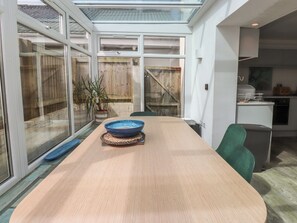 A modern kitchen with a dining area, large windows, and a view of the backyard. - Kiloran (Rhosneigr)