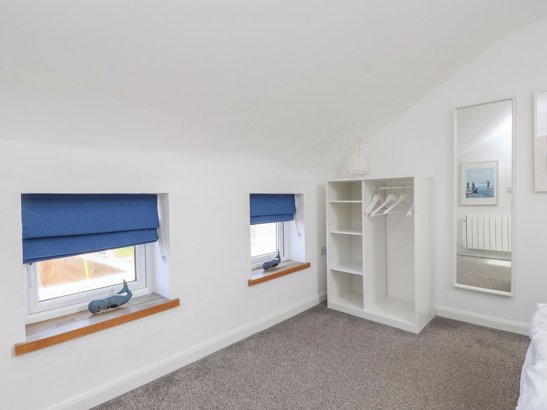 A room with two windows with blue blinds, a white wardrobe, and a hanging light fixture.