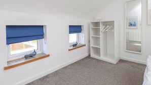 A room with two windows with blue blinds, a white wardrobe, and a hanging light fixture. - Kiloran (Rhosneigr)
