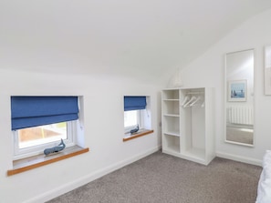 A room with two windows with blue blinds, a white wardrobe, and a hanging light fixture. - Kiloran (Rhosneigr)