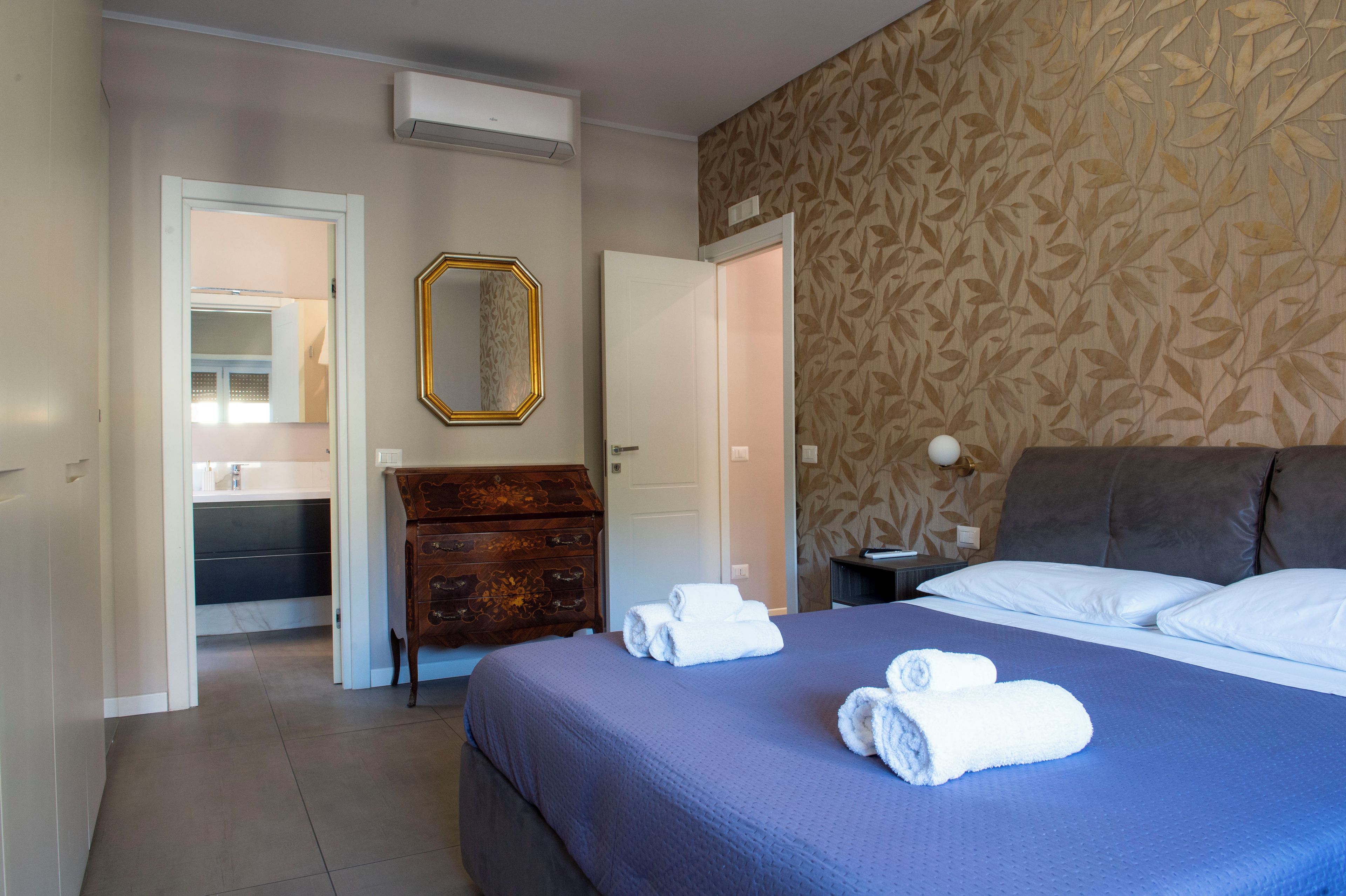 Een hotelkamer met een bed, een dressoir, een spiegel en een deur.