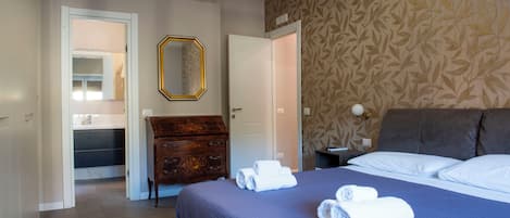 A hotel room with a bed, a dresser, a mirror, and a door.
