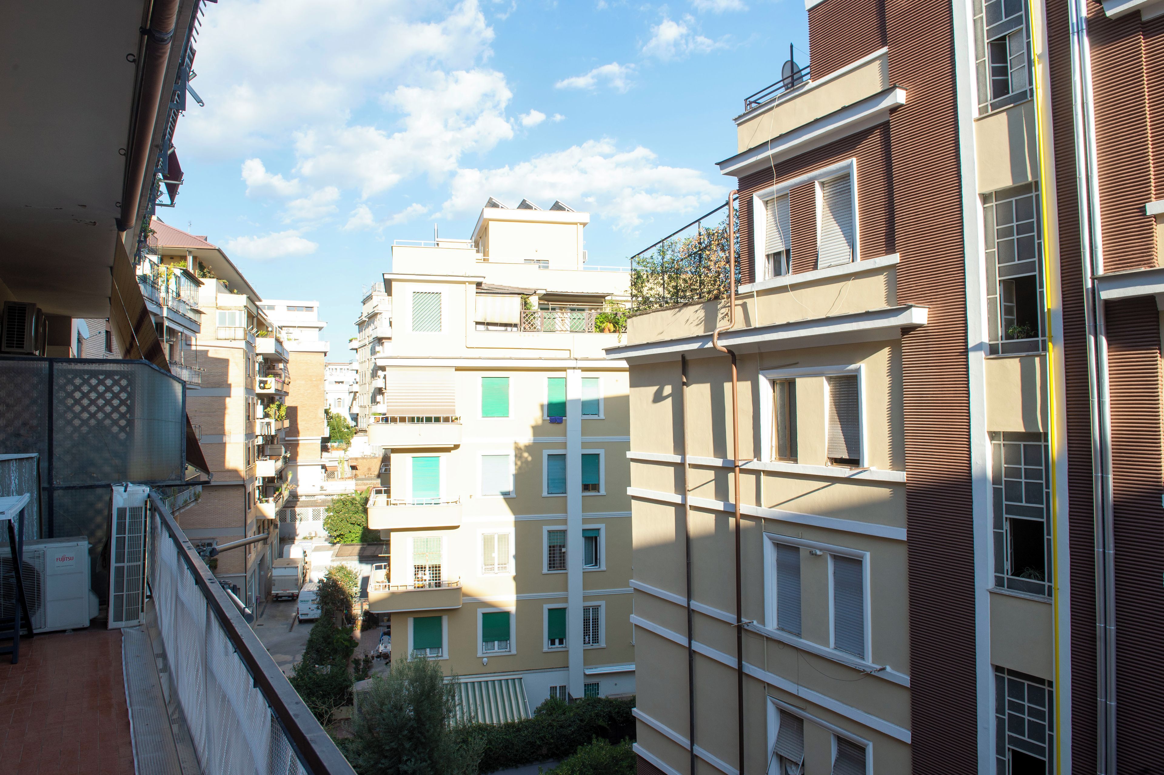 Un immeuble résidentiel à plusieurs étages, doté de balcons, d’un appareil de climatisation visible et surplombant un ciel dégagé.