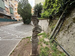 A statue in an outdoor urban setting with patterned pavement and buildings in the background. - Orietta Boutique Apartment Trastevere Train Station Monteverde Area (Roma)
