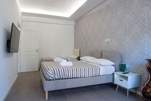 A modern hotel room with a bed, a bedside table, a TV, and a patterned wall. - Orietta Boutique Apartment, Trastevere Station (Roma)