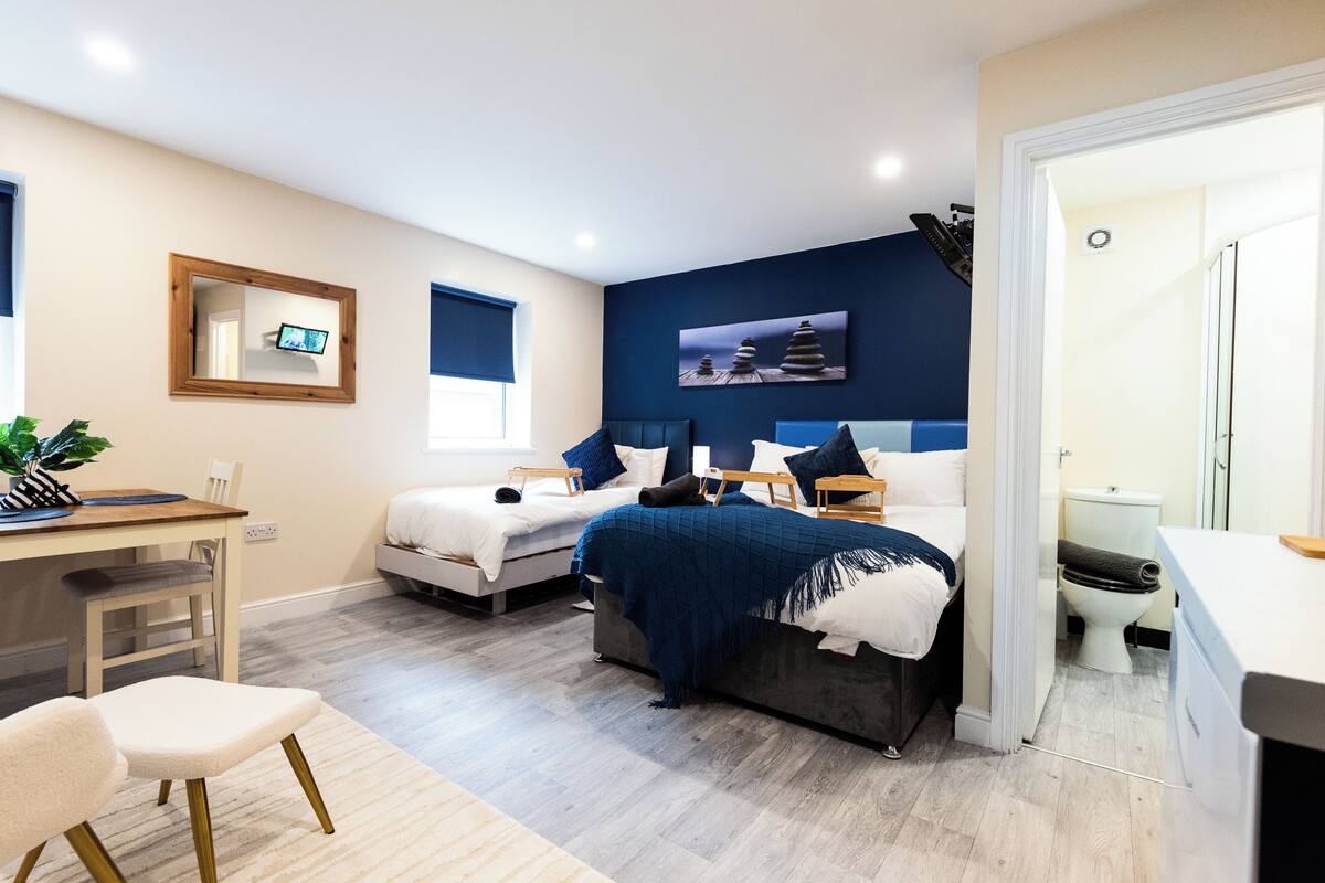 A bedroom with two beds, a desk, and a chair.
