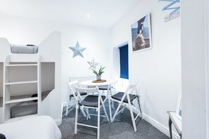 A room with a bunk bed, a round table with chairs, a potted plant, and a framed picture on the wall. - The Wellington Apart Hotel by Guestz (Blackpool)