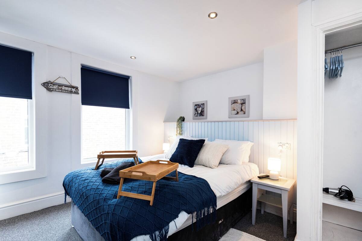 A bedroom with a bed, bedside table, and a window with blinds.