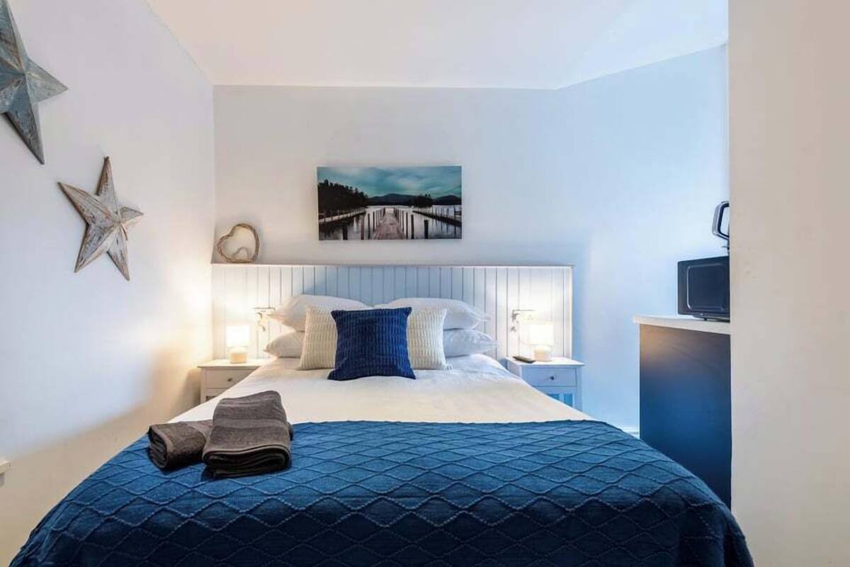 A bedroom with a bed, pillows, a heart-shaped decoration, a star, and a painting on the wall.