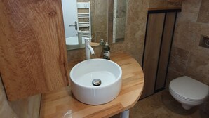Une salle de bain avec un lavabo blanc, un miroir, un porte-serviettes et des toilettes.