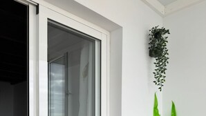 Ein Zimmer mit einer Schiebeglas-Tür, einem Sessel mit Kissen und einer hängenden Pflanze.