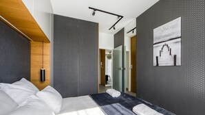 Quarto de hotel moderno com uma cama grande, uma mesa de cabeceira, uma luminária na parede e um quadro.