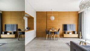 Uma sala de estar moderna com área de jantar, paredes de painel de madeira, uma TV de tela plana e um lustre globo único.
