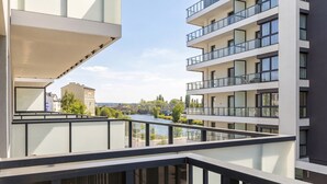 En modern hyresfastighet med balkonger som vetter mot en flod, med fri utsikt över floden och den omgivande vegetationen.