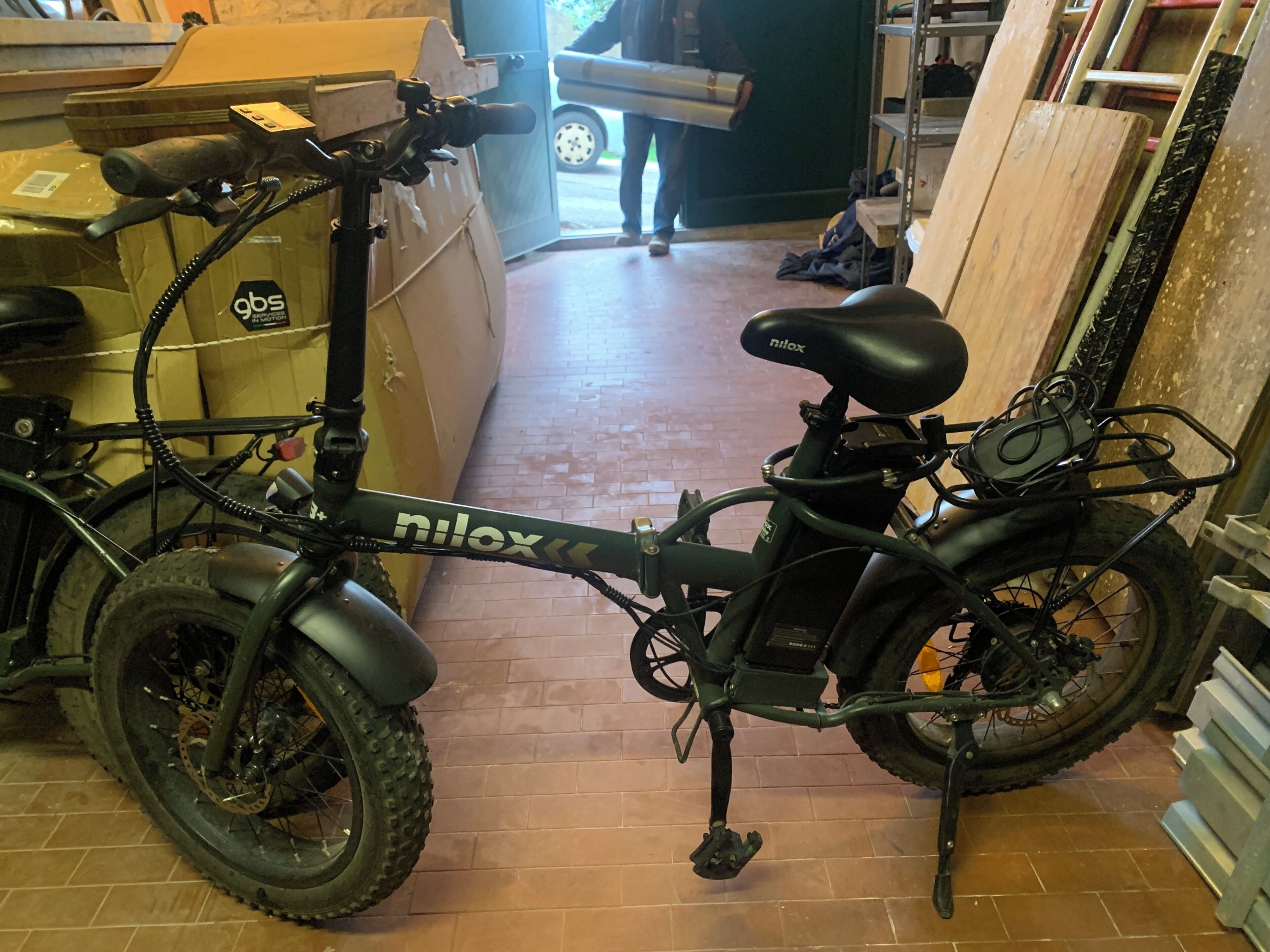 A bicycle with a black frame and a seat labeled 'nilox' parked indoors.