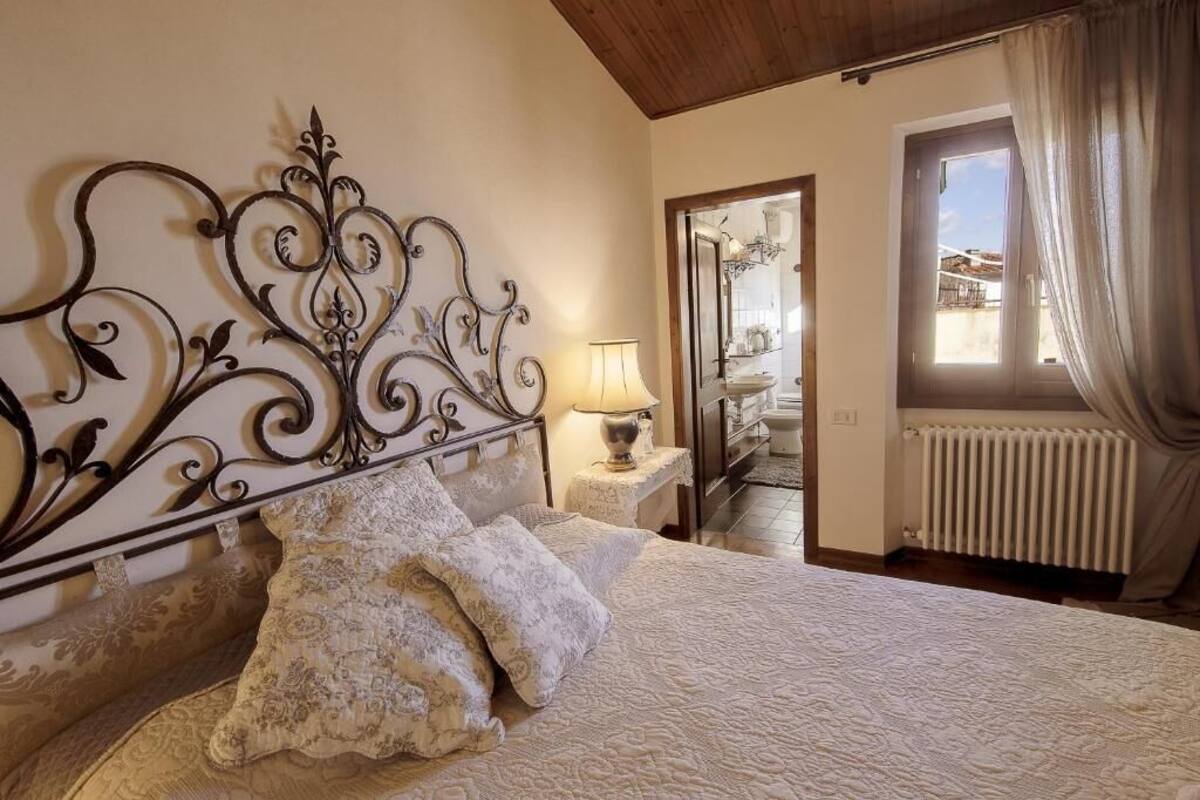A bedroom with a bed, a nightstand, a lamp, and a window with curtains.