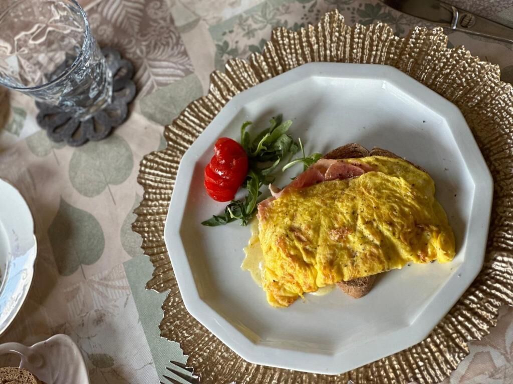 Een bord met een omelet, een kerstomaatje en groenten op een tafel met een placemat.