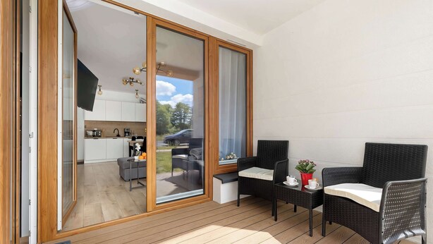 Ein Balkon mit Esstisch, Stühlen und einem kleinen Tisch mit einer Pflanze.