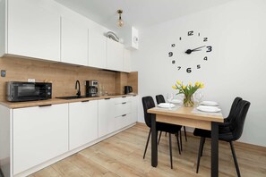 Una cocina moderna con armarios blancos, un microondas y un comedor con mesa de madera y sillas negras.