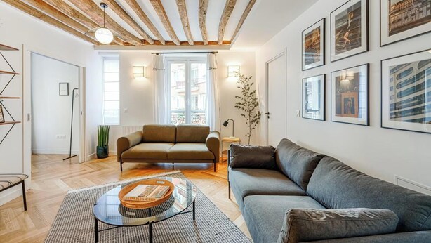 Ein Wohnzimmer mit Holzboden, zwei Sofas, einem Couchtisch und gerahmten Bildern an der Wand.