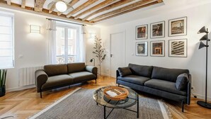 Ein Wohnzimmer mit zwei Sofas, einem Couchtisch, einer Stehlampe und gerahmten Bildern an der Wand.