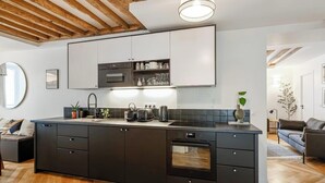 Eine moderne Küche mit Kochinsel, integrierten Geräten und einer Holzbalkendecke.