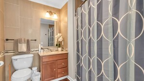 A bathroom with a toilet, sink, vanity, and shower curtain.