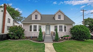 A two-story house with a front porch, a chimney, and a well-maintained lawn.