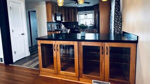 A kitchen with wooden cabinets, a black countertop, and pendant lighting.