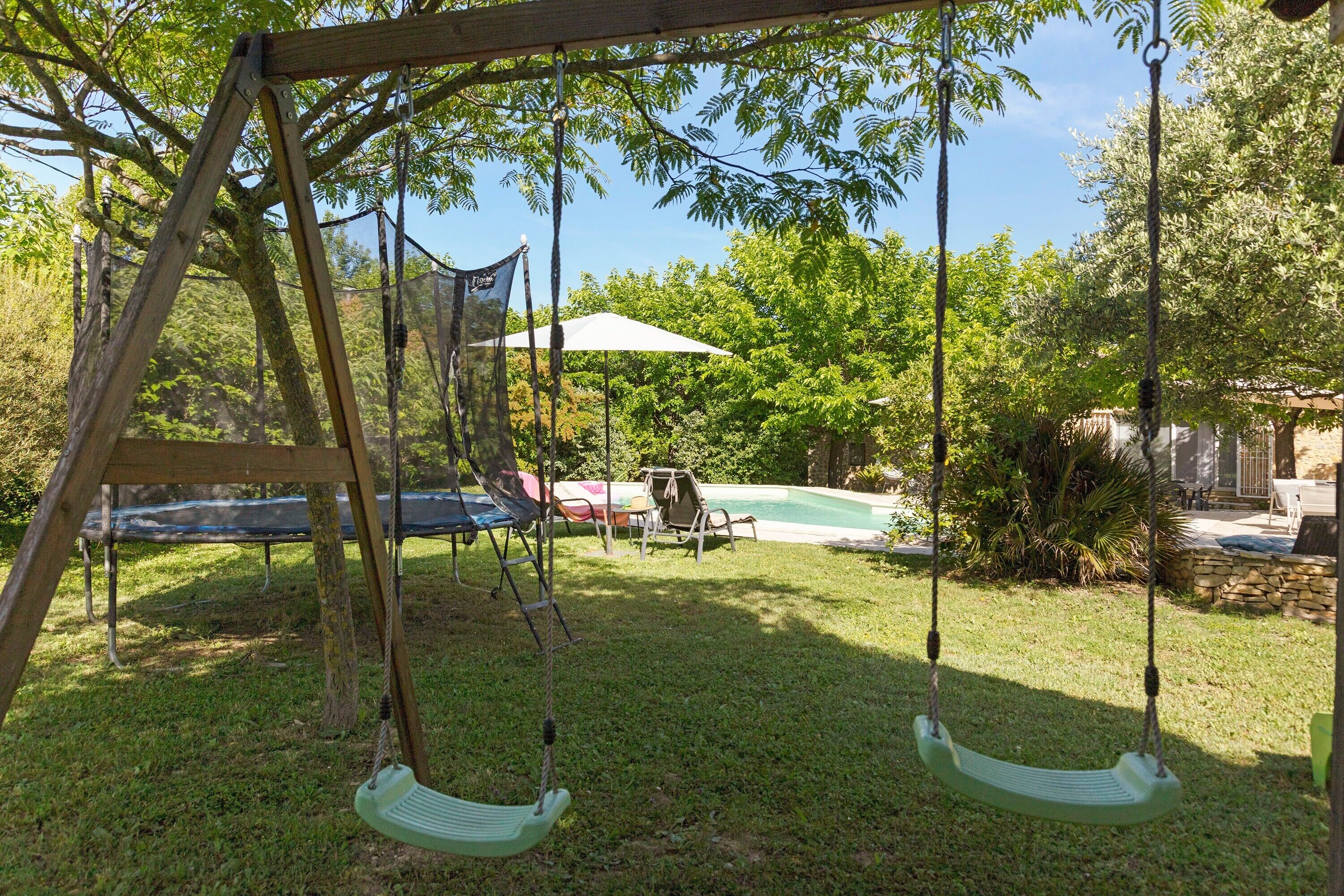 Ein Spielplatz aus Holz mit zwei Schaukeln, einem Pool und einer überdachten Terrasse im Garten.