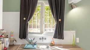 A kitchen with a window, a sink, a kettle, and a vase on the counter. - Loft with Private Pool, Wi-Fi, and Air Conditioning (Boisset-et-Gaujac)