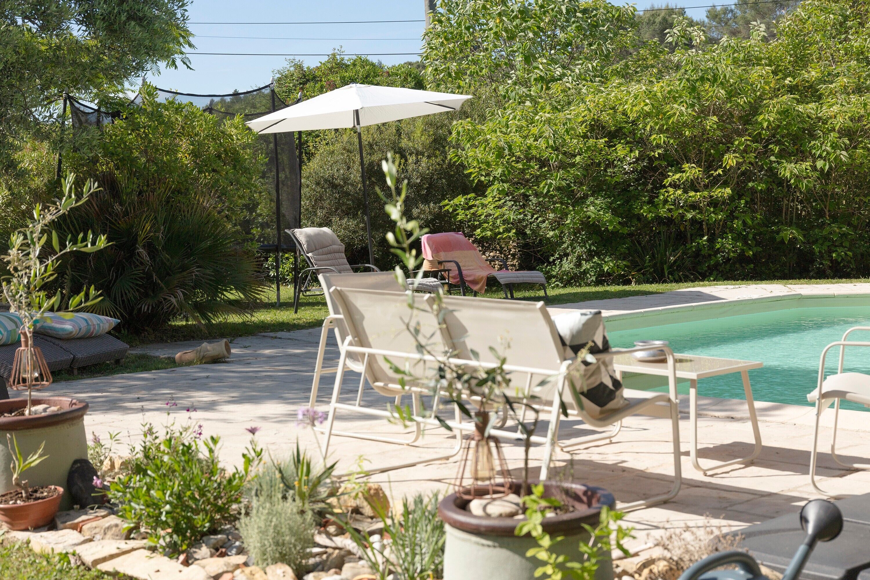 A poolside area with lounge chairs, a table, and an umbrella.