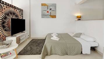 Een moderne slaapkamer met een bed, een televisie, een kunstwerk aan de muur en een bedlampje.