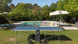 A ping pong table in a grassy outdoor area with a pool and lounge chairs in the background. - Loft with Private Pool, Wi-Fi, and Air Conditioning (Boisset-et-Gaujac)
