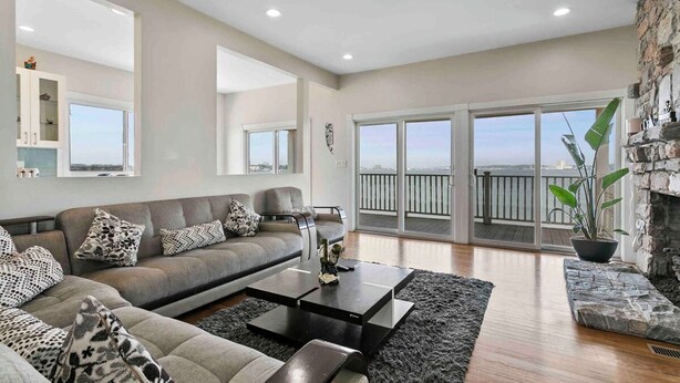 A modern living room with a grey sofa, black coffee table, and a stone fireplace. - Beautiful Bayfront Home • Heated Pool & Jacuzzi (West Haven)
