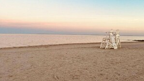 A beach with a lifeguard tower and a calm sea. - Beautiful Bayfront Home • Heated Pool & Jacuzzi (West Haven)