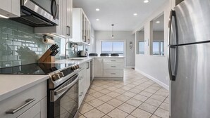 A modern kitchen with white cabinets, stainless steel appliances, and a tiled floor. - Beautiful Bayfront Home • Heated Pool & Jacuzzi (West Haven)