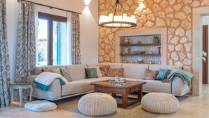 Ein Wohnzimmer mit einer Couch, Poufs, einem Couchtisch und einer Steinwand mit Regalen.