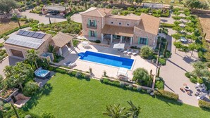 Ein großes Haus mit Swimmingpool, Sitzgelegenheiten im Freien und einem Garten.