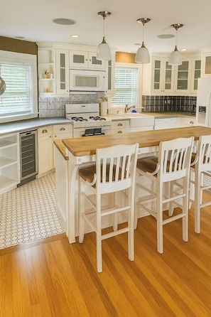 A kitchen with white cabinets, a wooden island, and pendant lighting. - Beautiful cozy home w jacuzzi & dock for boat (New Haven)