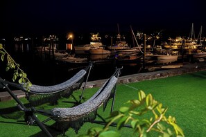 Marina à noite com barcos atracados, uma rede e uma área gramada.
