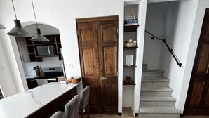 Une cuisine moderne avec un coin bar, un plancher en bois et un escalier menant à une mezzanine.