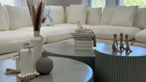 Una sala de estar moderna con un sofá modular, una mesita redonda y adornos decorativos.