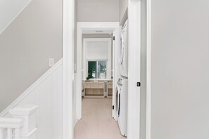 A narrow hallway with a washing machine, a window with blinds, and a door leading to a room. - Huge Home Near Beach front with Pool and Hot Tub (New Haven)