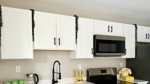 Une cuisine moderne avec des meubles blancs, des appareils en acier inoxydable et un plancher en bois.